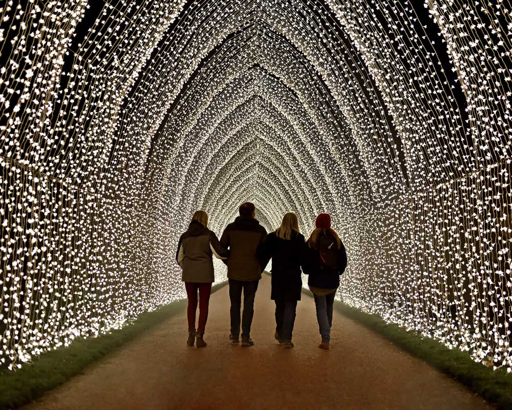 People walking through a tunnel of sparking lights at night.